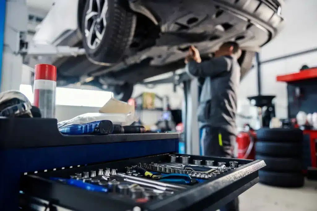 reparation-auto-garagiste mécanicien effectuant une réparation auto sous un véhicule en atelier